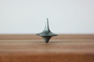 Metal spinning top toy balancing on top of a wood surface.